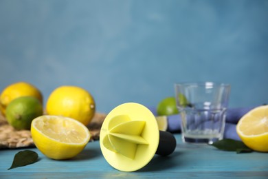 Photo of Citrus reamer, fresh lemons and limes on light blue wooden table