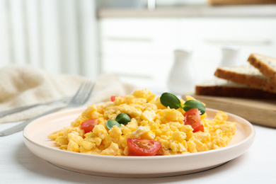 Tasty scrambled eggs with sprouts and cherry tomato on white wooden table