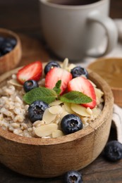 Photo of Tasty oatmeal with strawberries, blueberries and almond flakes in bowl on wooden table, closeup