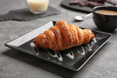 Photo of Plate with tasty croissant and sauce on grey table. French pastry