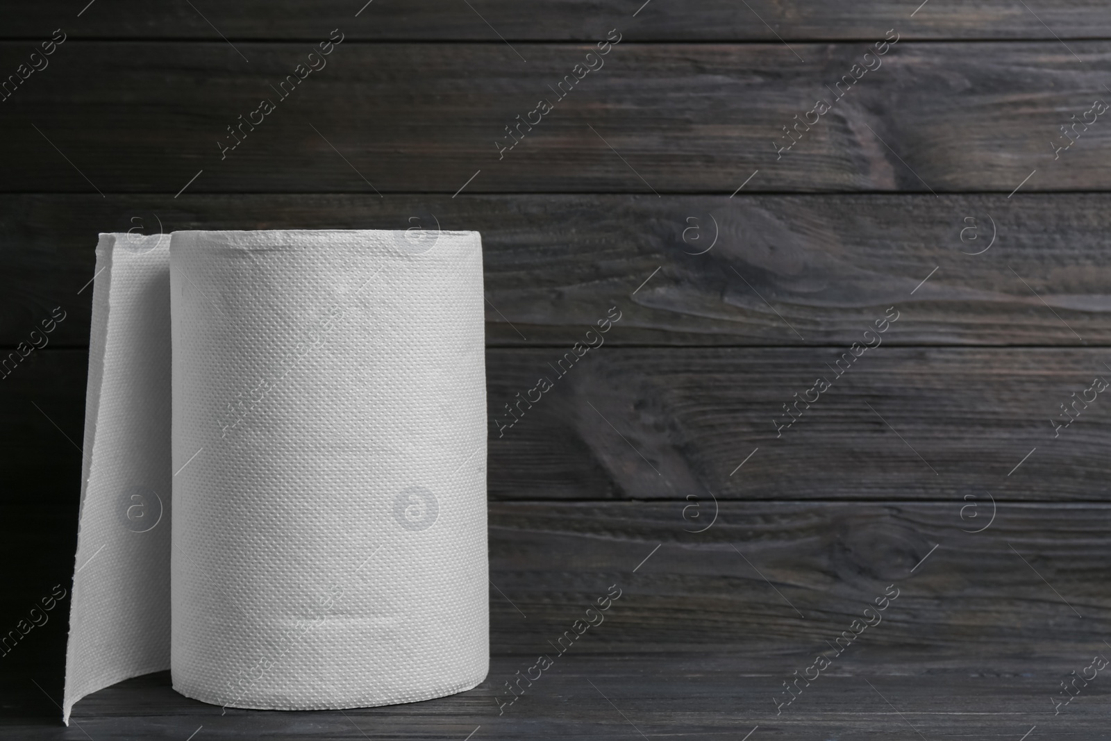 Photo of Roll of paper towels on wooden table, space for text