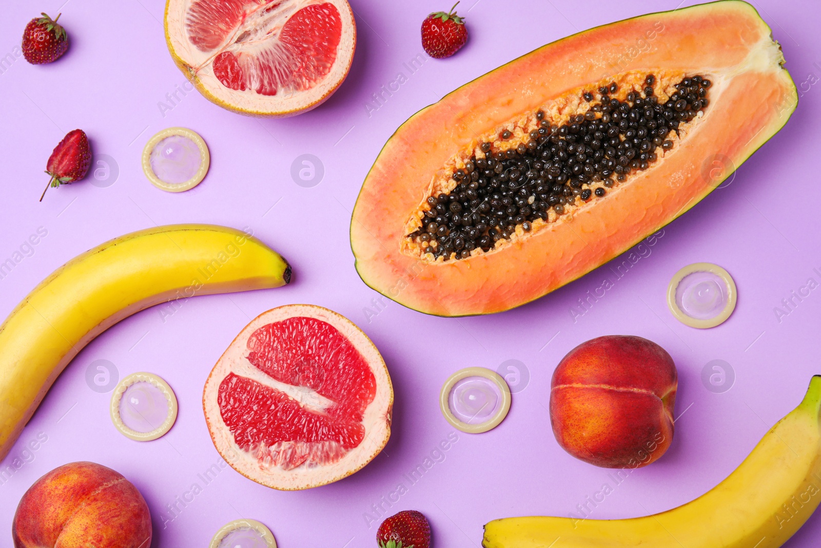 Photo of Flat lay composition with condoms and exotic fruits on lilac background. Erotic concept