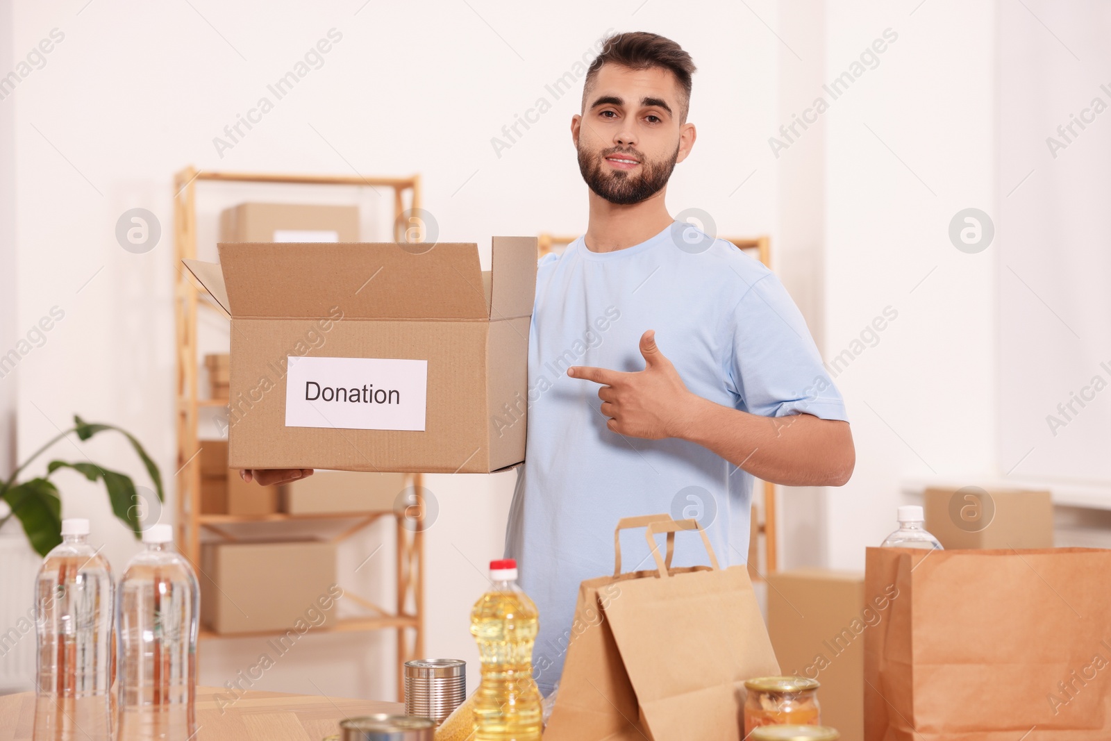 Photo of Volunteer with donation box and food products on table in warehouse