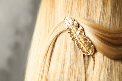 Photo of Woman with beautiful gold hair clip on grey background, closeup