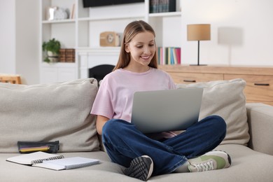 Online learning. Teenage girl with laptop on sofa at home