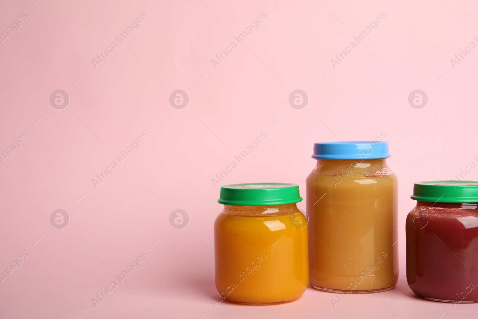 Photo of Jars with healthy baby food on pink background, space for text