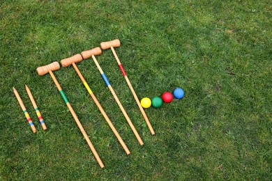 Set of croquet equipment on green grass, above view. Space for text