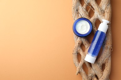 Bottle and jar of cosmetic products on orange background, top view. Space for text