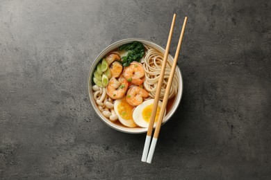 Delicious ramen with shrimps and chopsticks on grey table, top view. Noodle soup