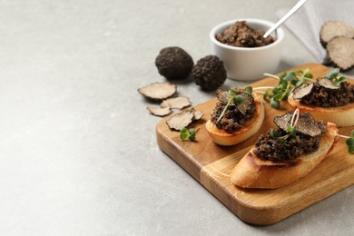 Tasty bruschettas with truffle paste on grey table, space for text