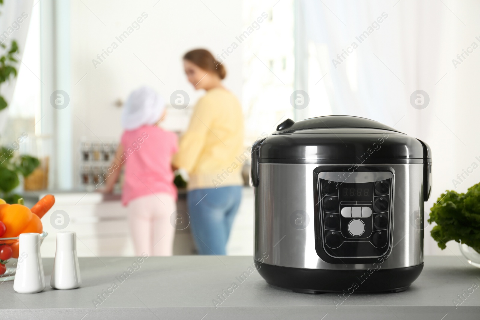 Photo of Modern multi cooker and products on table in kitchen