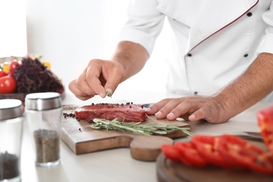 Photo of Professional chef cooking meat on table in kitchen, closeup