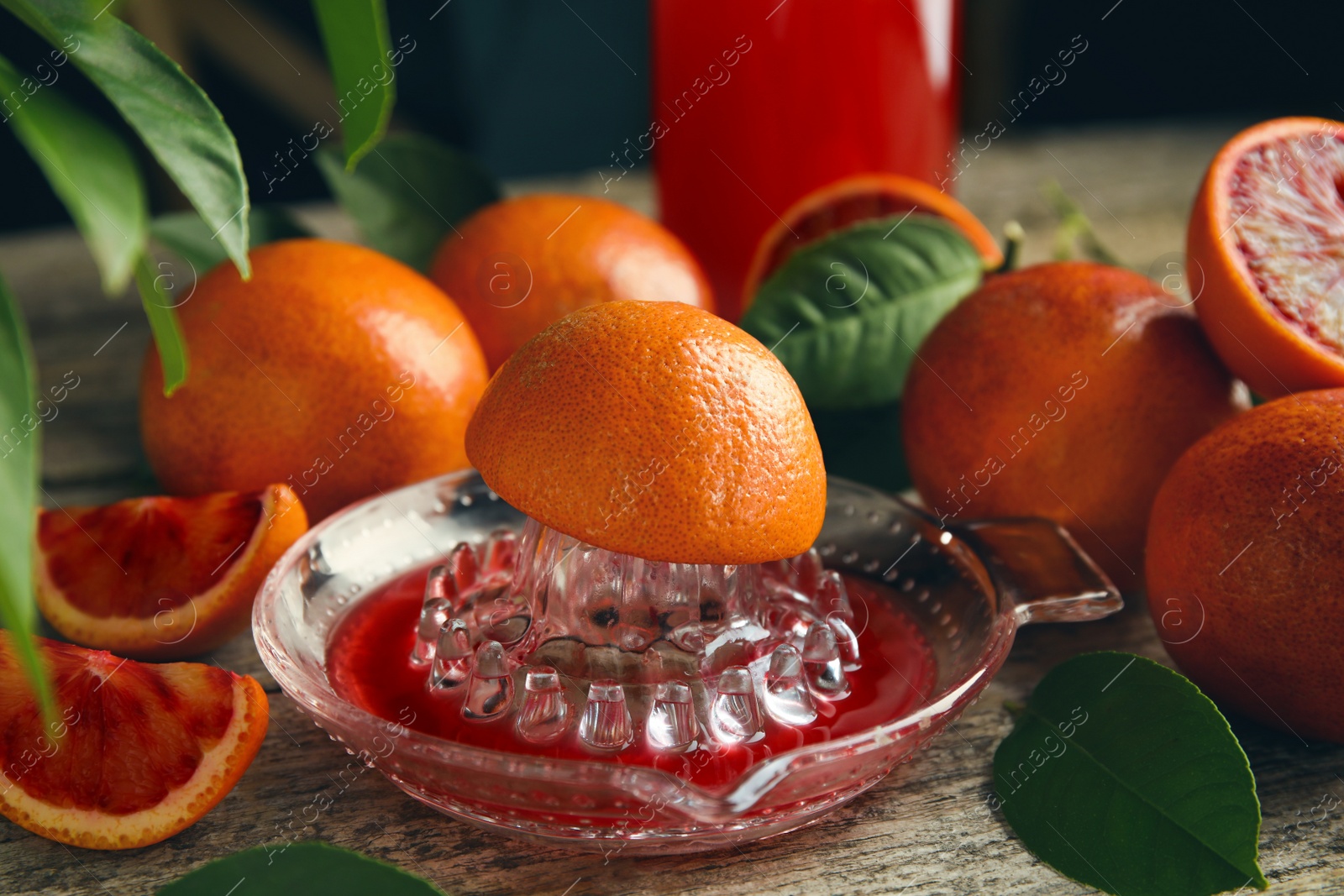 Photo of Squeezer with half of sicilian orange on wooden table