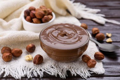 Bowl with delicious chocolate paste and nuts on wooden table, closeup