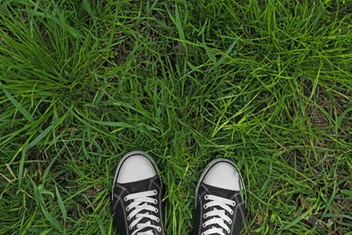 Person in gumshoes standing on green grass outdoors, top view