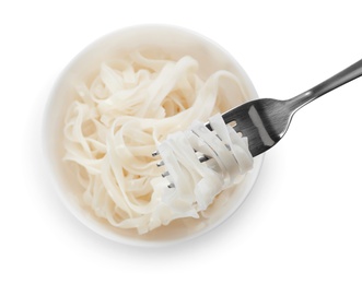 Photo of Fork with rice noodles over bowl on white background, top view