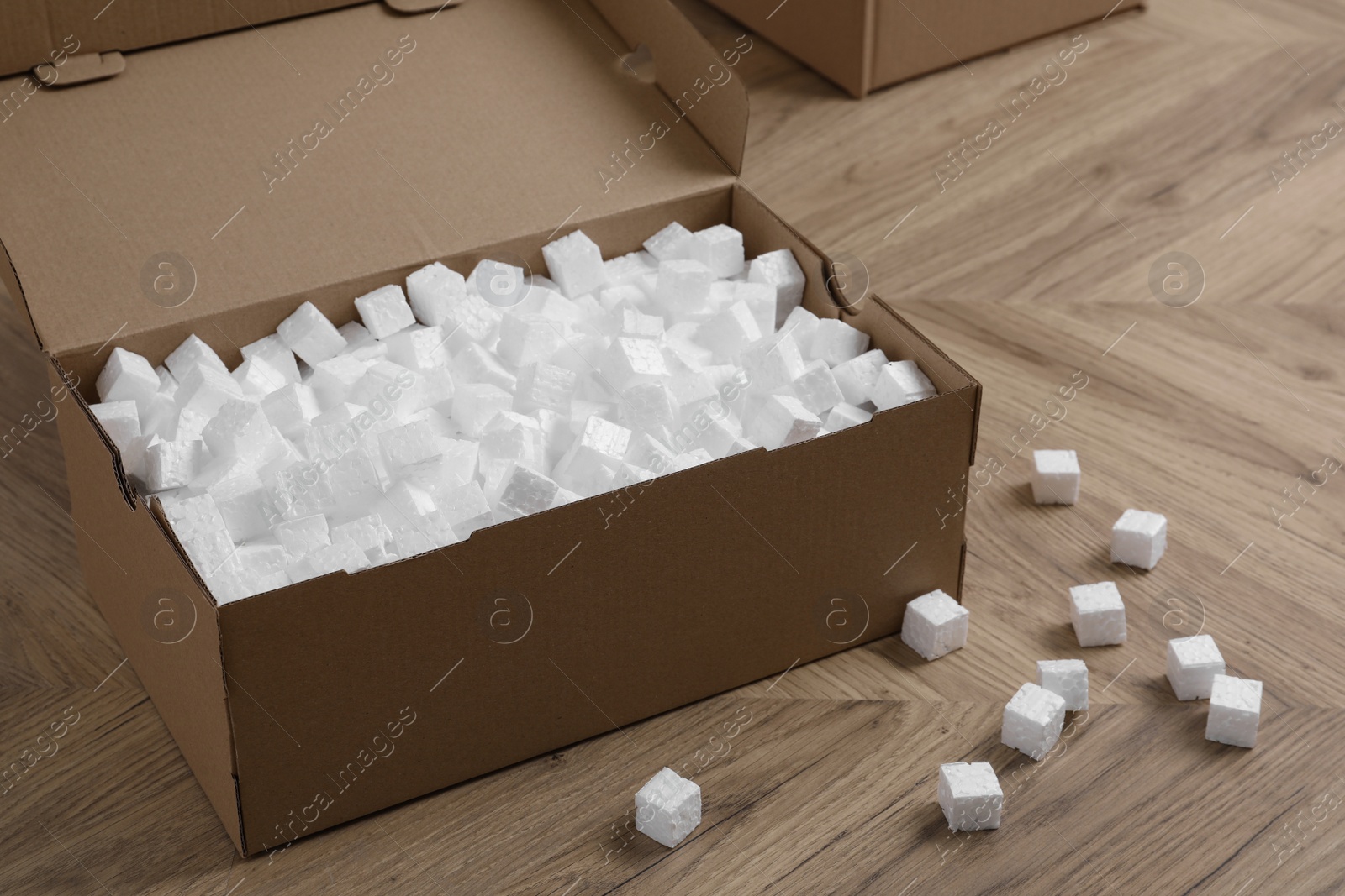 Photo of Cardboard box and styrofoam cubes on wooden floor