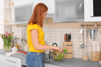 Tired housewife preparing vegetable salad in kitchen