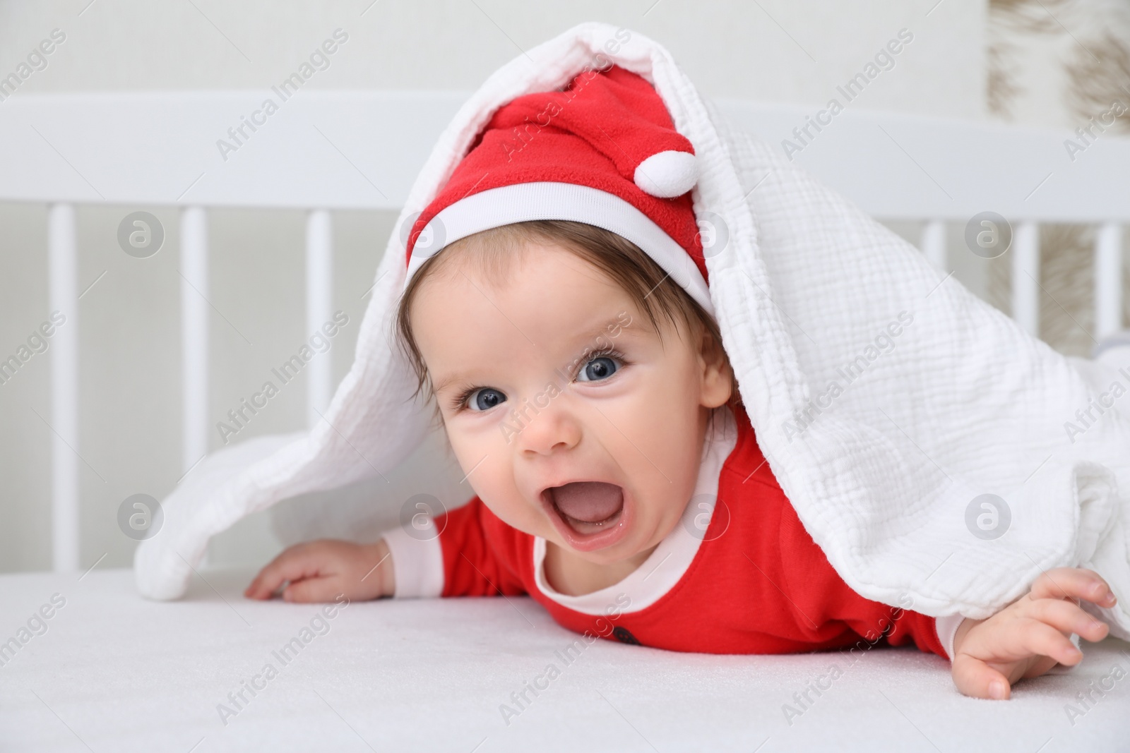 Photo of Cute baby wearing festive Christmas costume in crib