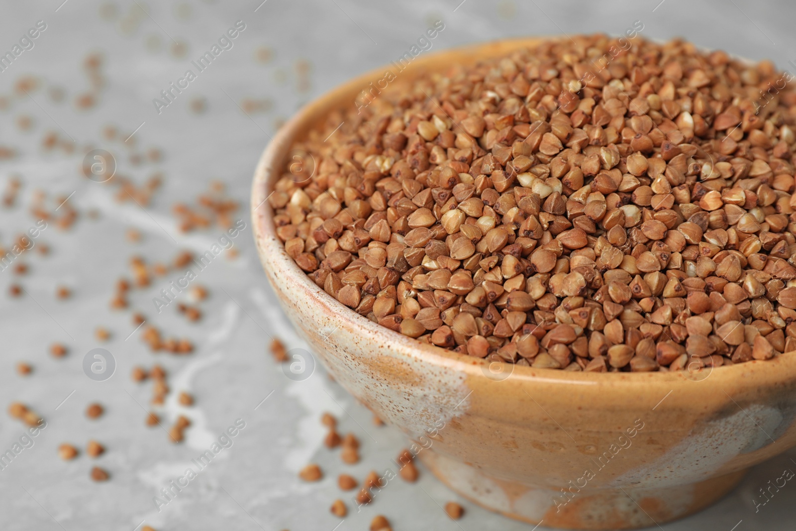 Photo of Uncooked buckwheat in bowl on table, closeup