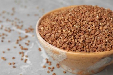 Photo of Uncooked buckwheat in bowl on table, closeup