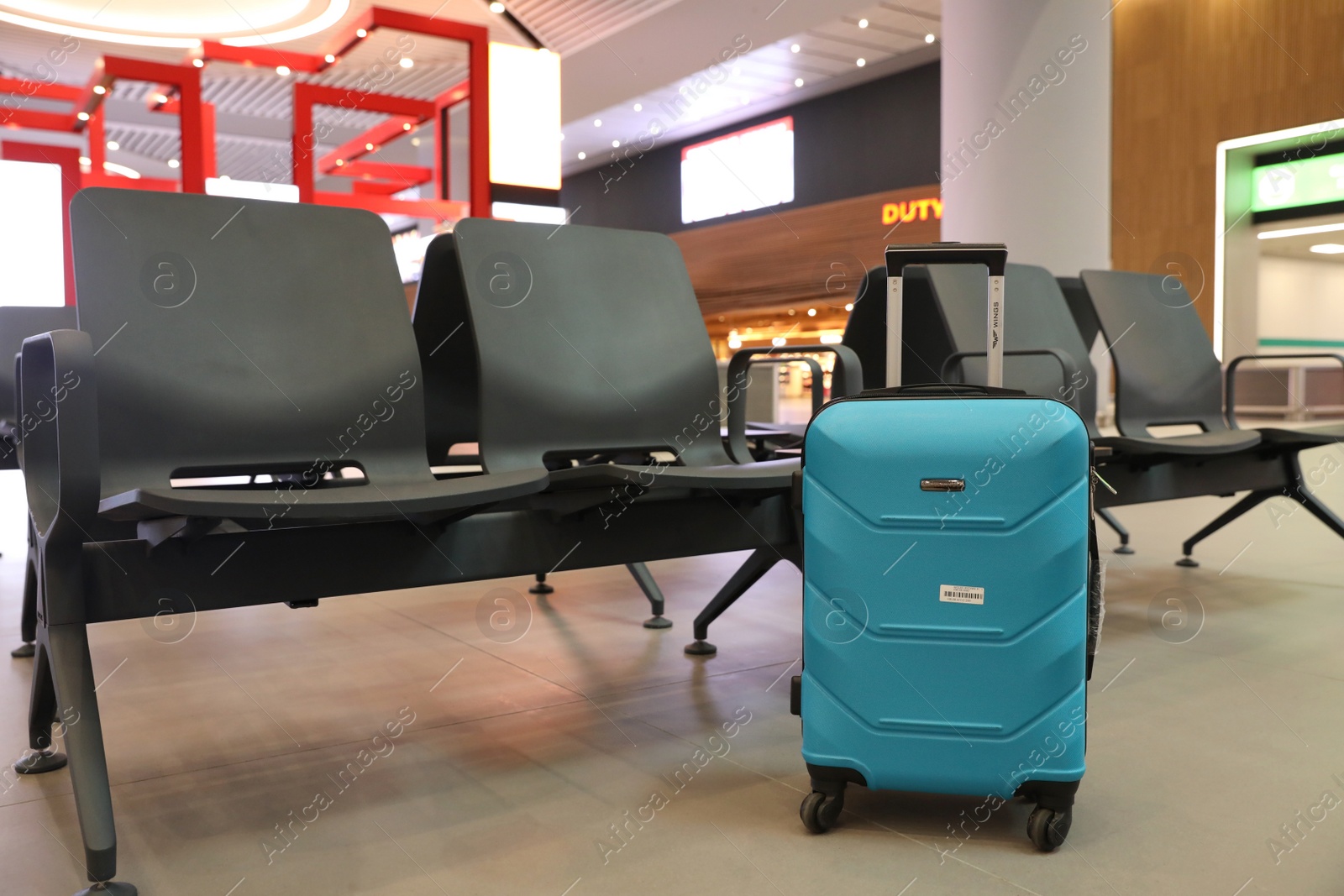 Photo of ISTANBUL, TURKEY - AUGUST 6, 2019: Bright modern suitcase near bench in airport