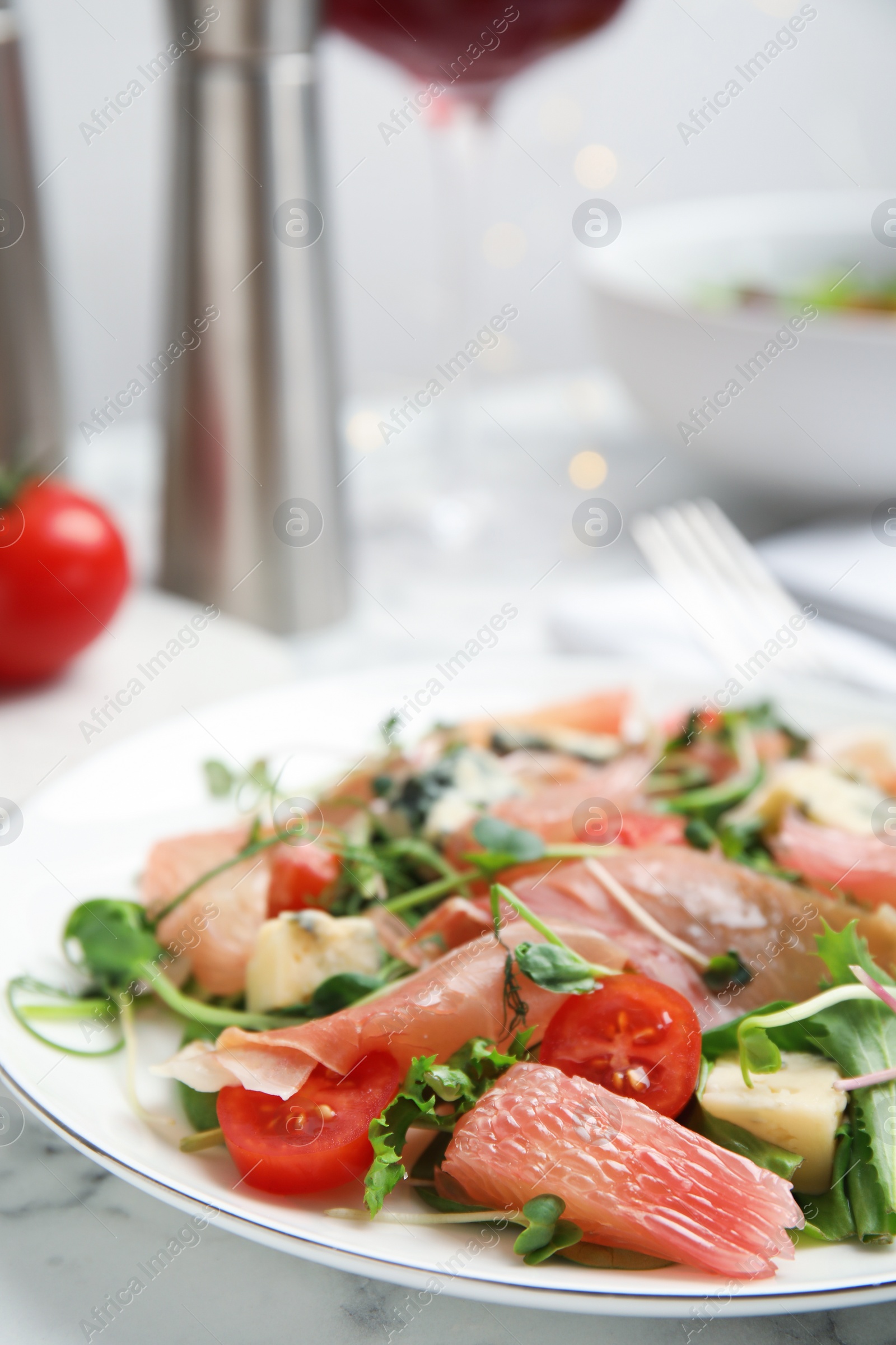 Photo of Delicious pomelo salad with prosciutto served on white marble table, closeup. Space for text