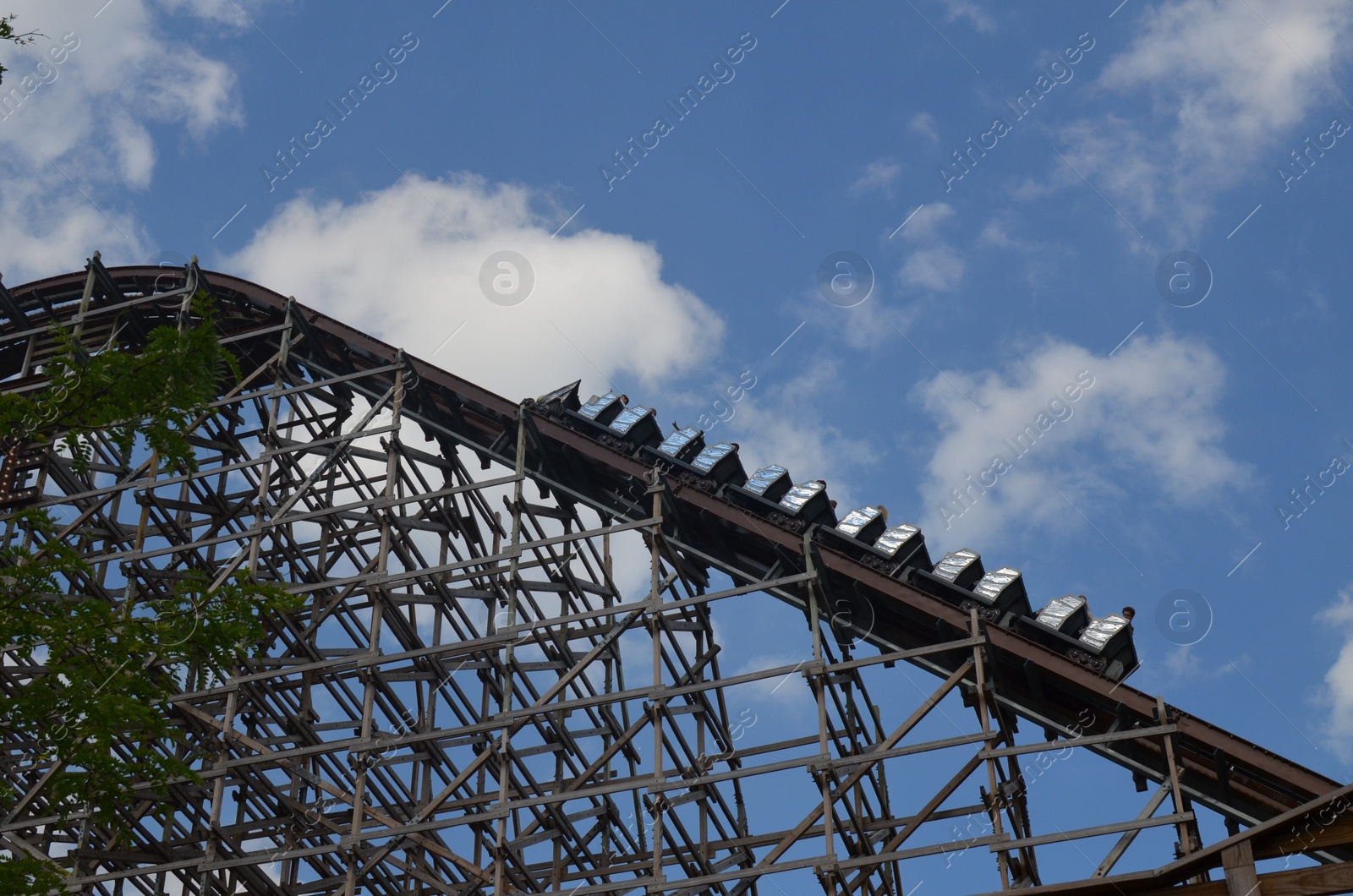 Photo of Amusement park. Beautiful large rollercoaster against blue sky, low angle view