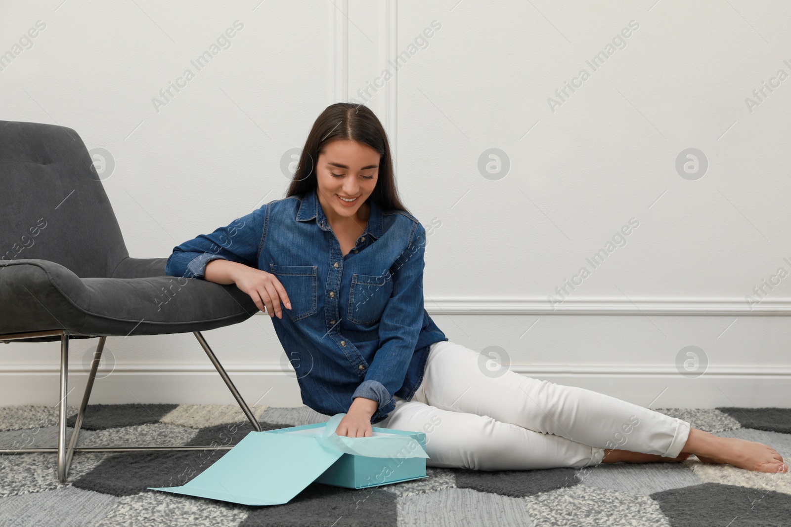 Photo of Happy young woman with parcel at home. Internet shopping