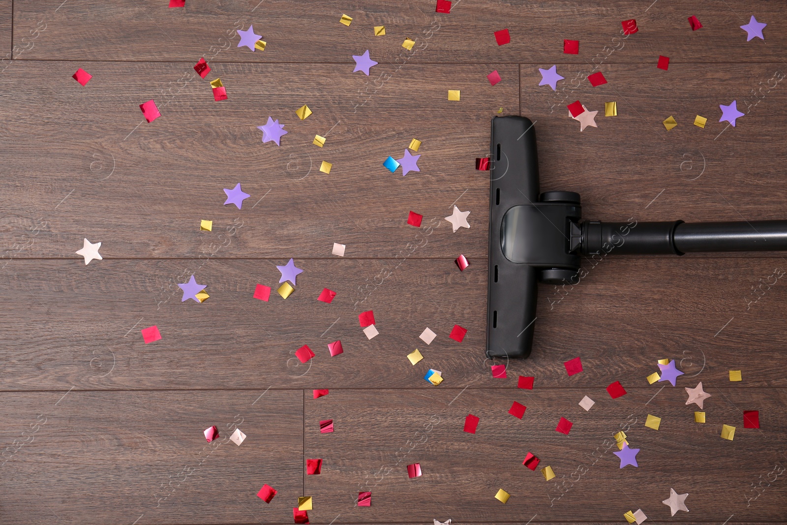 Photo of Vacuuming confetti from wooden floor, top view. Space for text