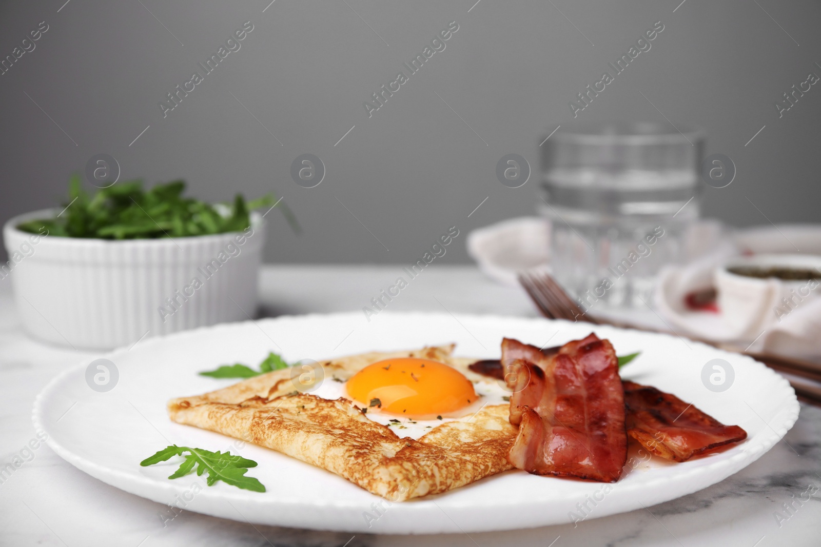 Photo of Delicious crepe with egg served on white marble table. Breton galette