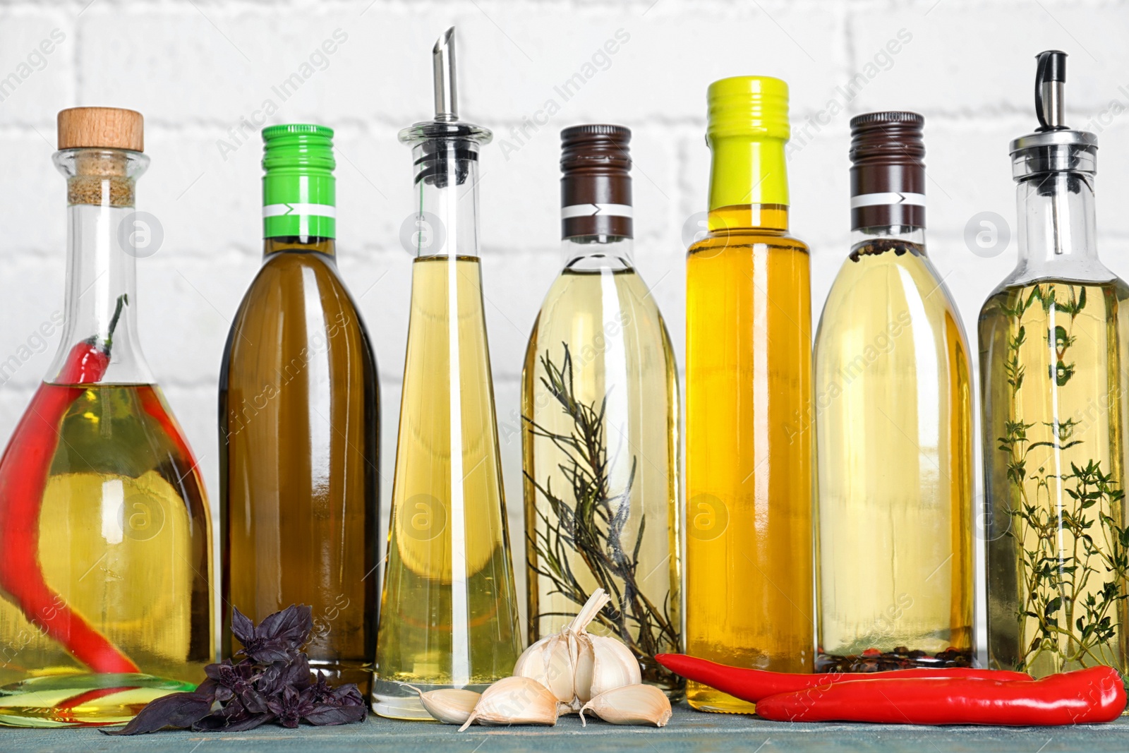 Photo of Different cooking oils on blue wooden table