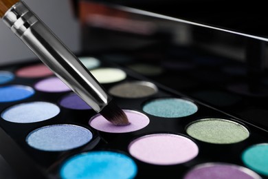 Photo of Colorful eyeshadow palette with brush, closeup view