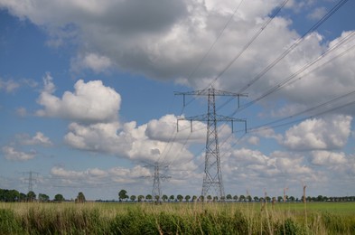 Photo of Modern high voltage towers in field on sunny day