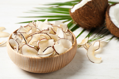 Photo of Tasty coconut chips on white wooden table