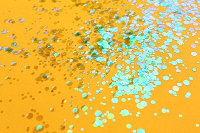 Photo of Shiny bright glitter scattered on orange background
