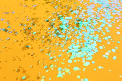 Shiny bright glitter scattered on orange background