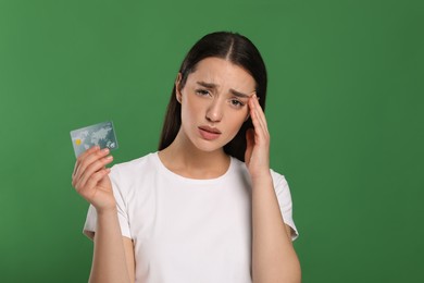 Photo of Worried woman with credit card on green background. Debt problem