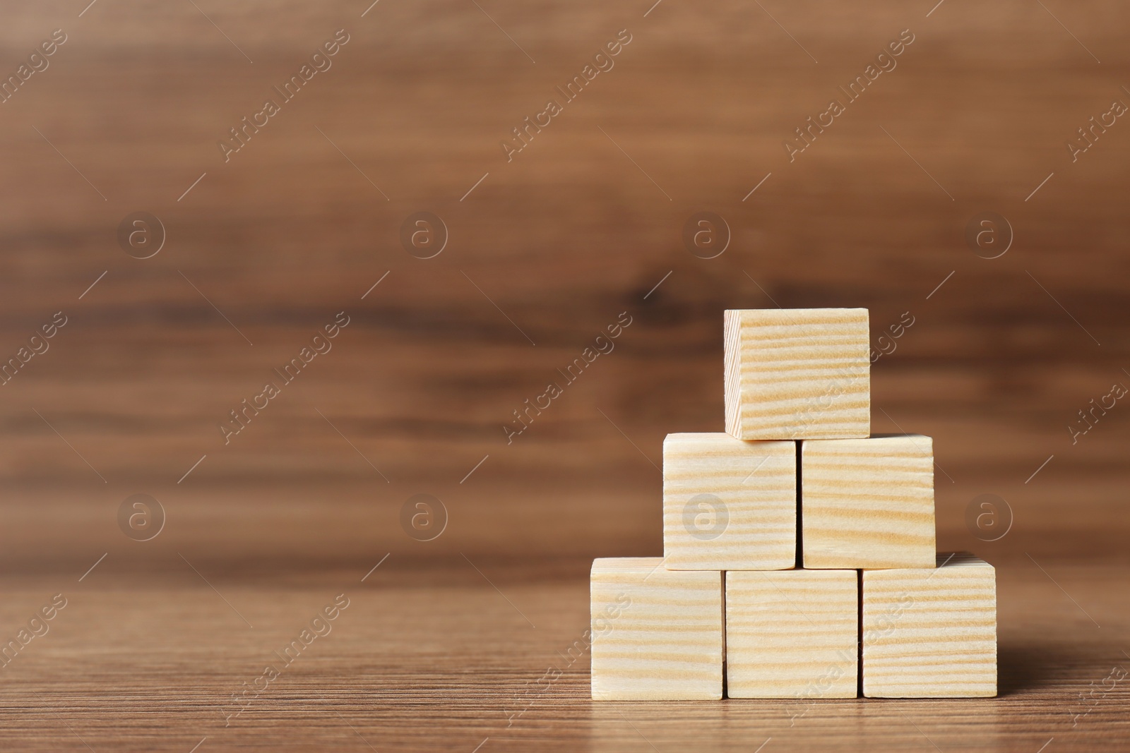 Photo of Pyramid of cubes on wooden background, space for text. Idea concept