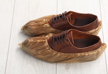 Photo of Men`s shoes in shoe covers on light wooden floor