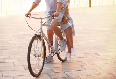 Photo of Young couple riding bicycle outdoors on summer day, closeup