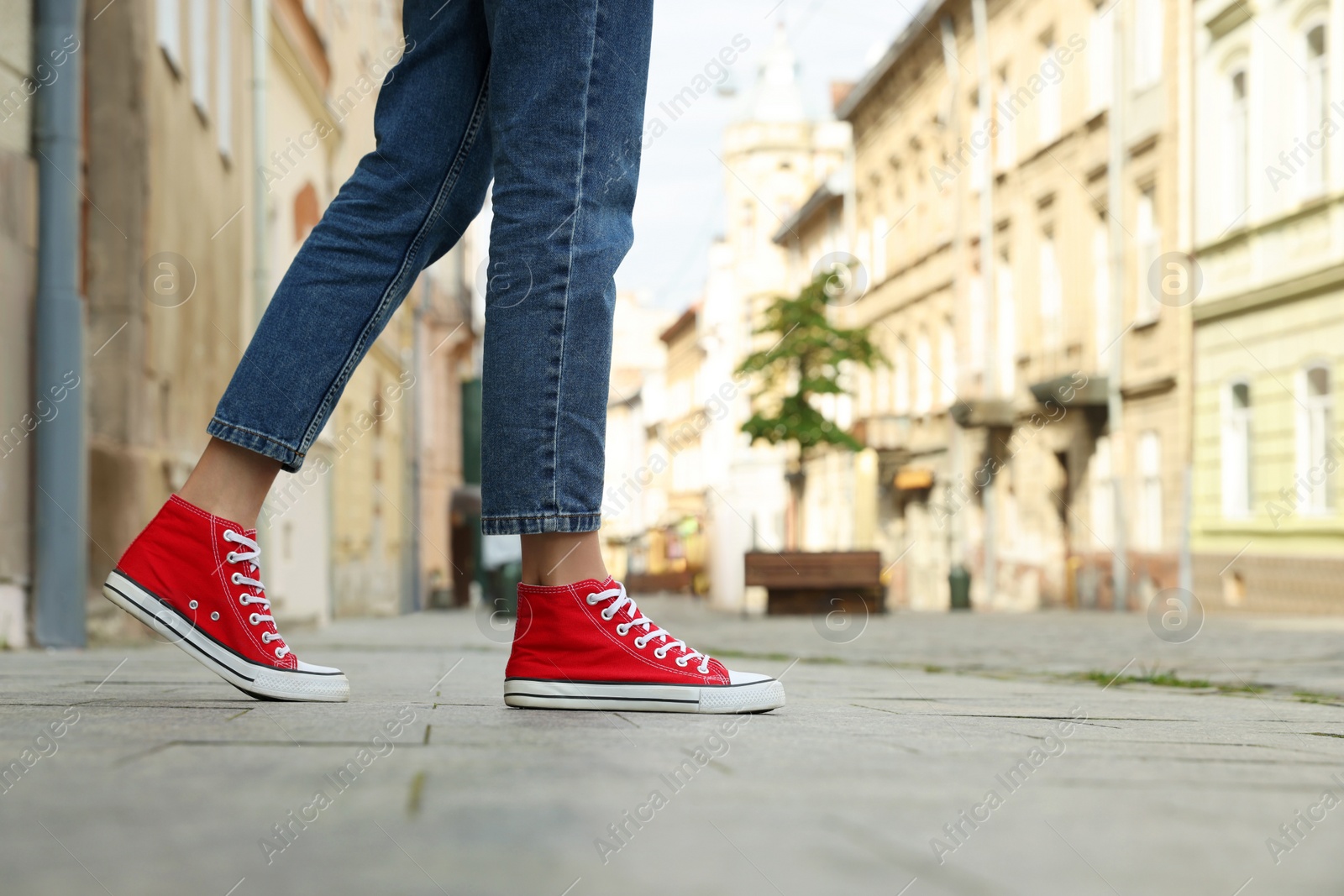 Photo of Woman in stylish sneakers walking on city street, closeup. Space for text