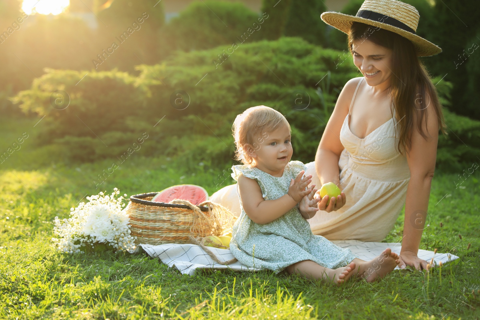 Photo of Mother with her baby daughter having picnic in garden on sunny day