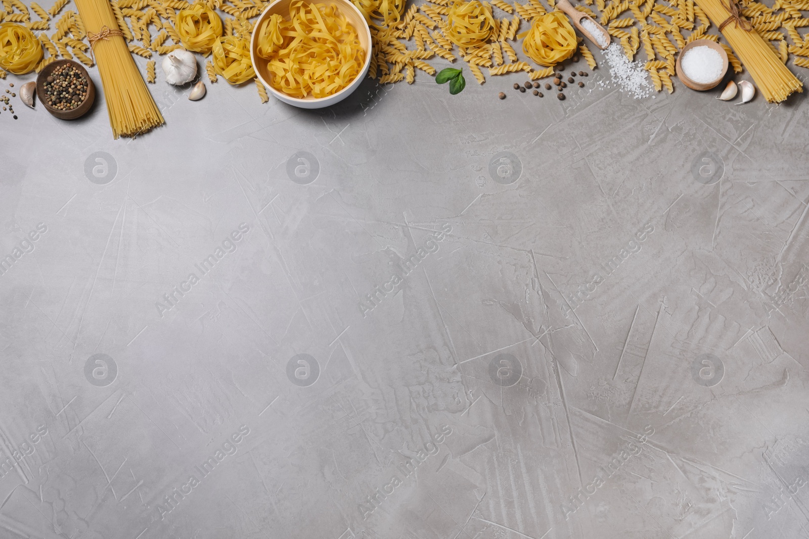 Photo of Flat lay composition with different types of pasta on grey table, space or text