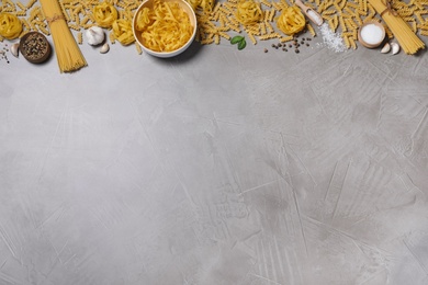 Flat lay composition with different types of pasta on grey table, space or text