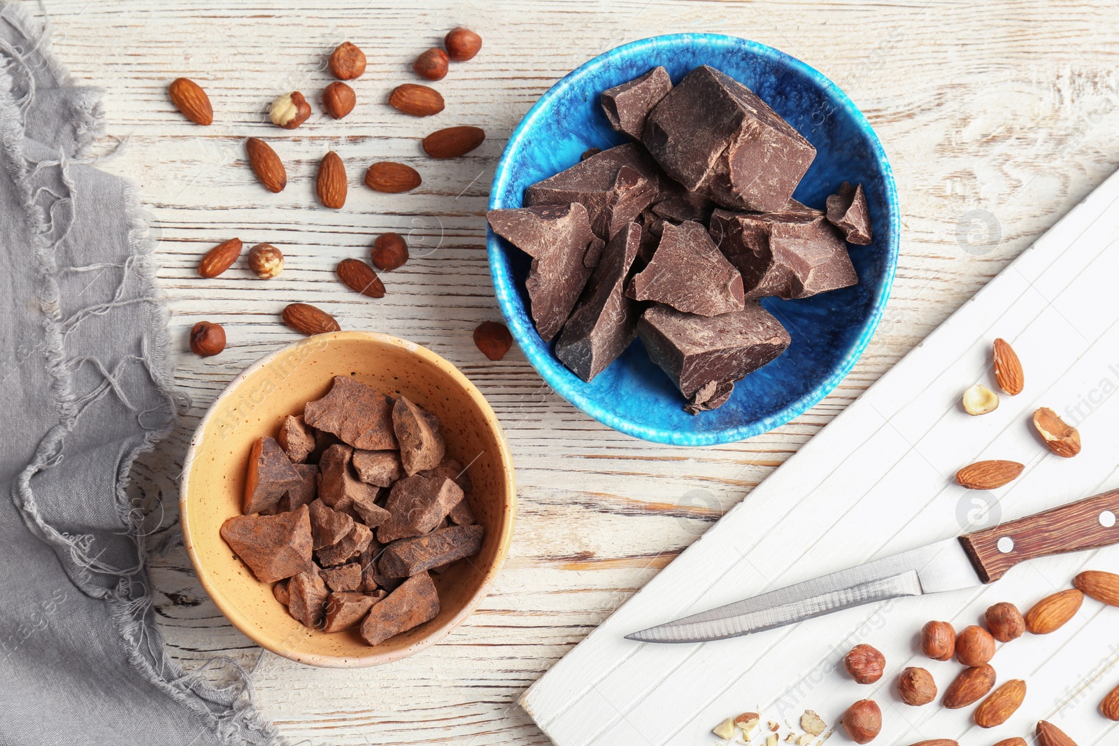 Photo of Bowls with pieces of delicious dark chocolate on wooden table, top view