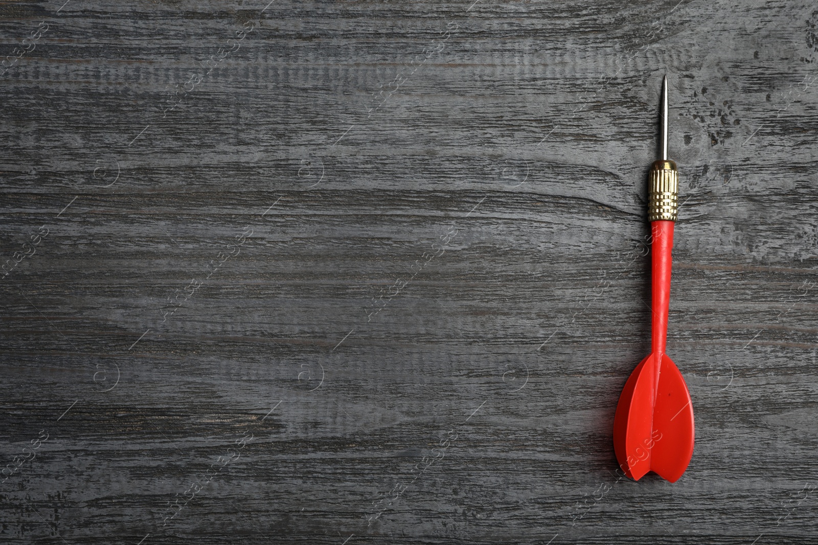 Photo of Dart arrow on wooden background, top view. Space for text