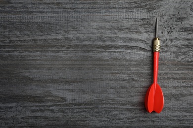 Dart arrow on wooden background, top view. Space for text