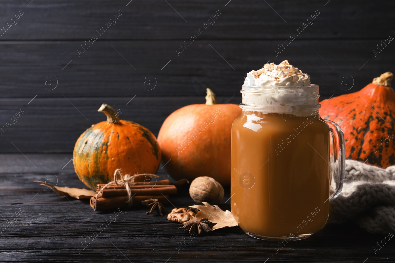 Photo of Mason jar with tasty pumpkin spice latte on wooden table