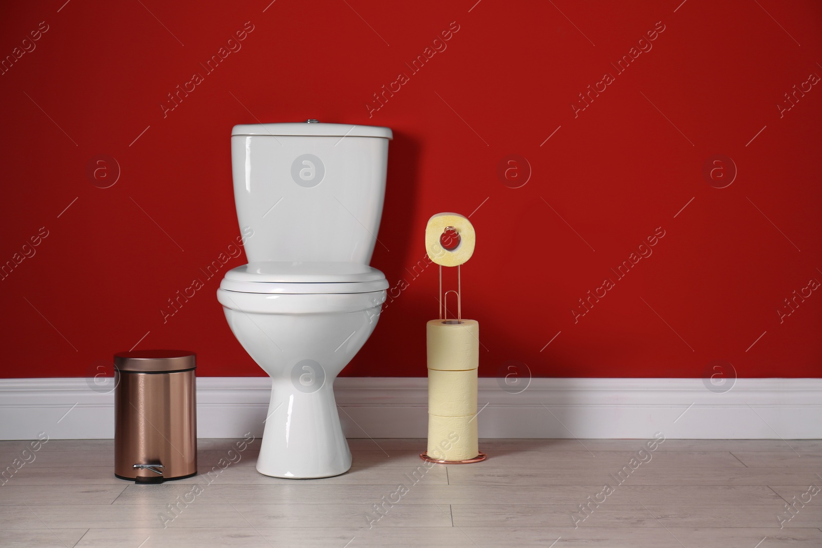 Photo of Toilet bowl with paper rolls and trash bin in restroom. Space for text